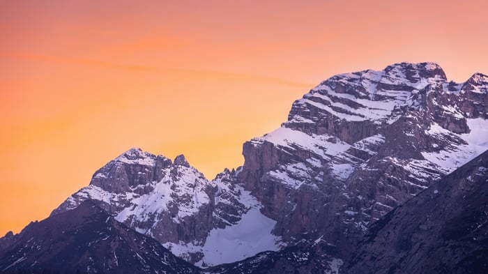 Snow-capped mountains against an orange sky