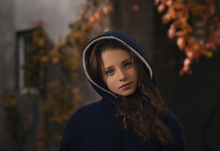 Girl in a blue hoodie with autumn leaves