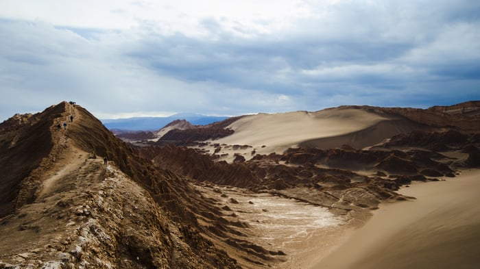 People hiking on a mountain ridge in a desert landscape