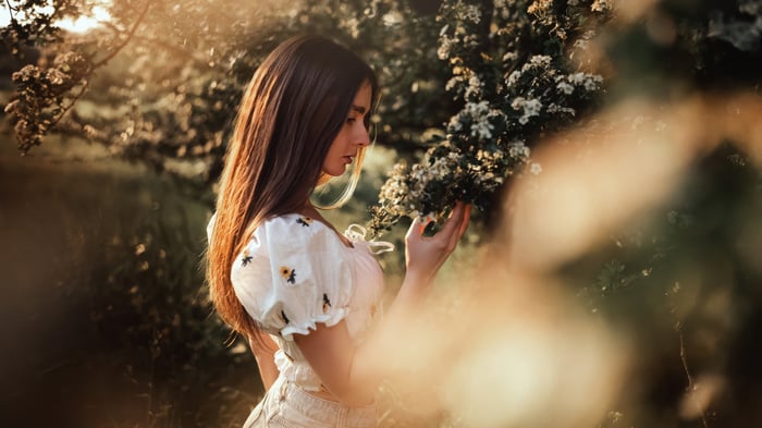 Young woman in floral top smelling flowers at dusk
