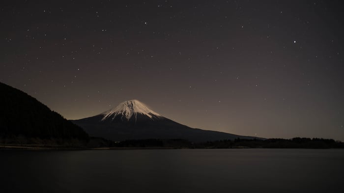 Mount Fuji at night over a lake with stars