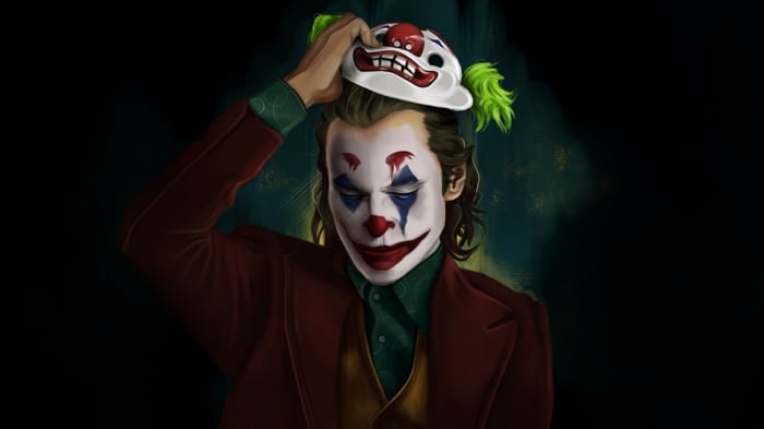 Joker holding a clown mask above his head