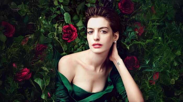 Anne Hathaway in a green dress surrounded by roses