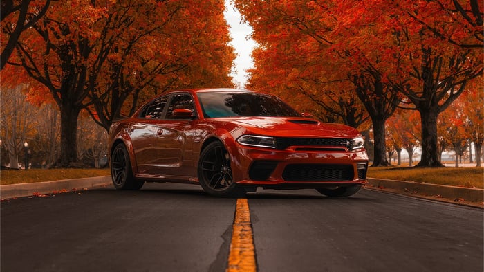 Red Dodge Charger on a Road Lined with Autumn Trees