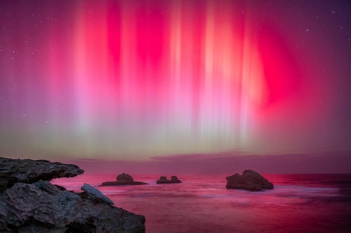 Aurora over the ocean with rocks