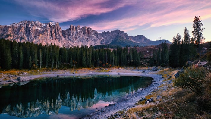 Lake reflection of mountains and pine forest at sunset