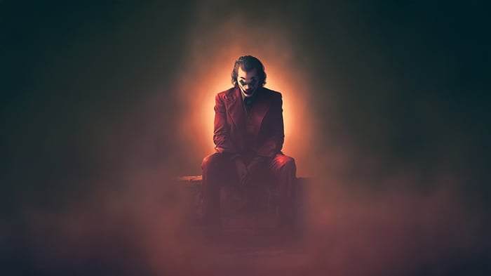 Joker sitting in red suit with orange glow