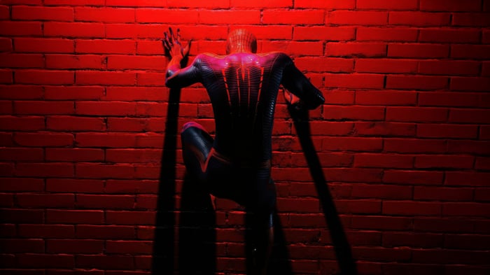 Spider-Man climbs a brick wall under red light
