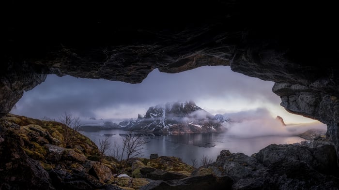 Cave view of foggy mountains and lake in Norway