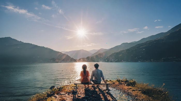 Couple sitting on a bench by a lake at sunset