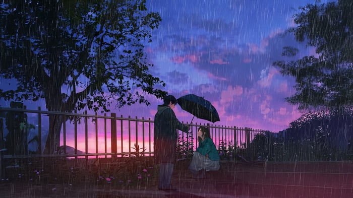 Couple sharing an umbrella in the rain at sunset