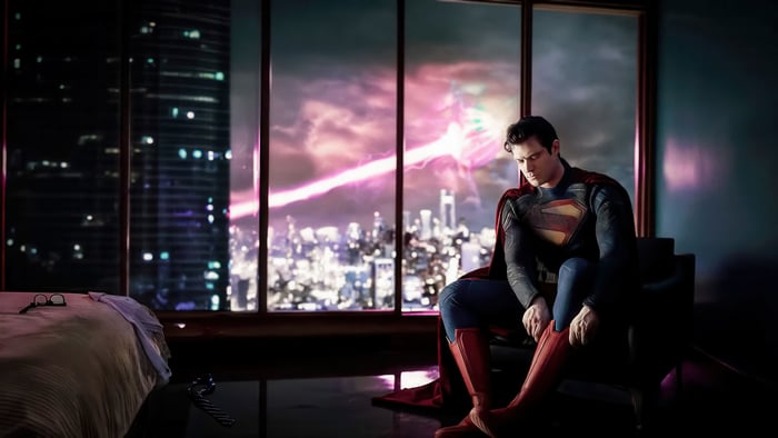 Superman putting on his boots in a room overlooking a city