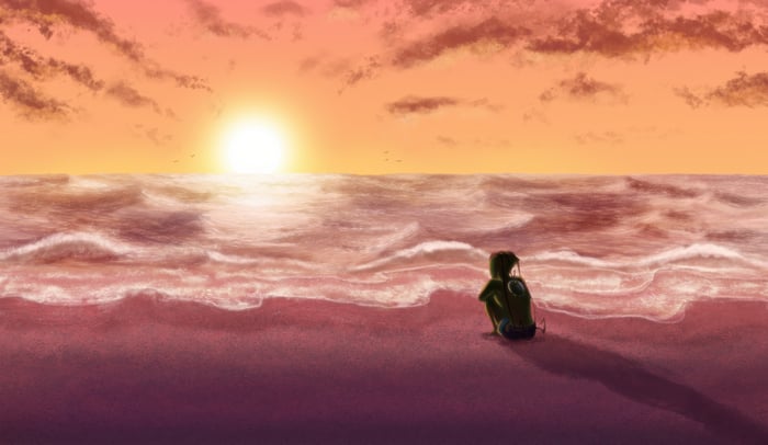 Person sitting on a beach at sunset