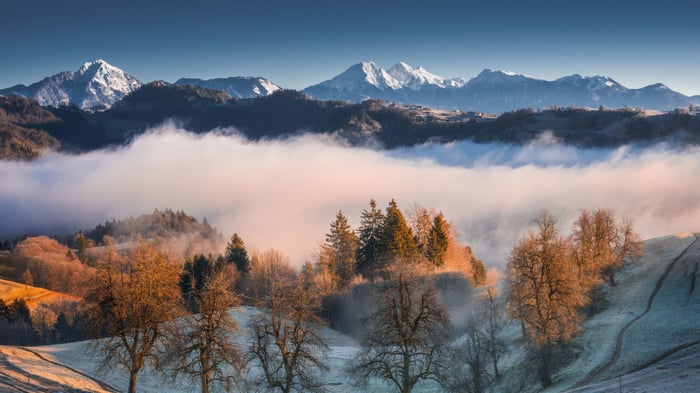 Misty Mountain Peaks Above Frosty Trees in Morning Light