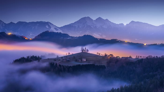 Mountain church on a hill at dawn with fog