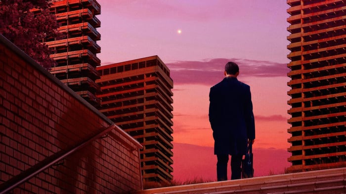 Man in suit looking at city skyline at sunset