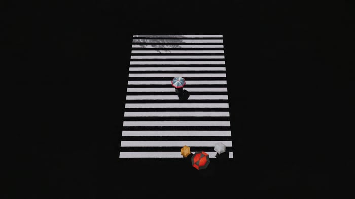 People with umbrellas on a monochrome crosswalk