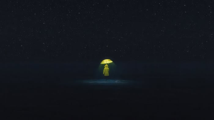 A person in a yellow raincoat holding a yellow umbrella under the stars