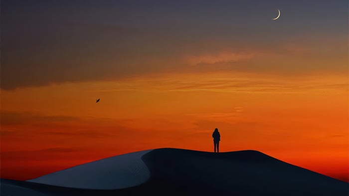 Silhouette of a person on a sand dune at sunset