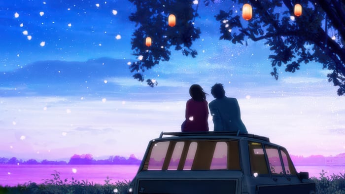 Couple Sitting on Car Roof Under Lanterns