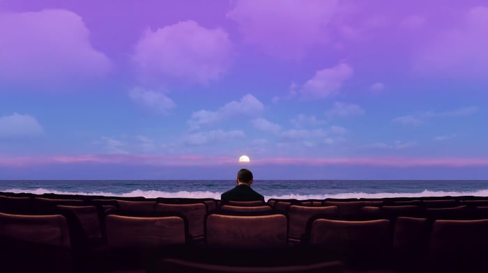 Man watches sunset from theater seats by the ocean