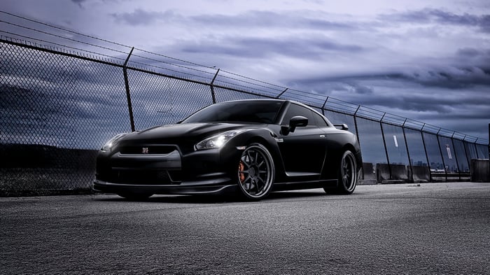 Black Nissan GT-R R35 parked by a fence