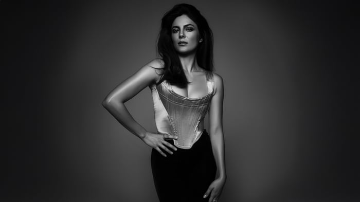 Monica Barbaro in a corset and skirt