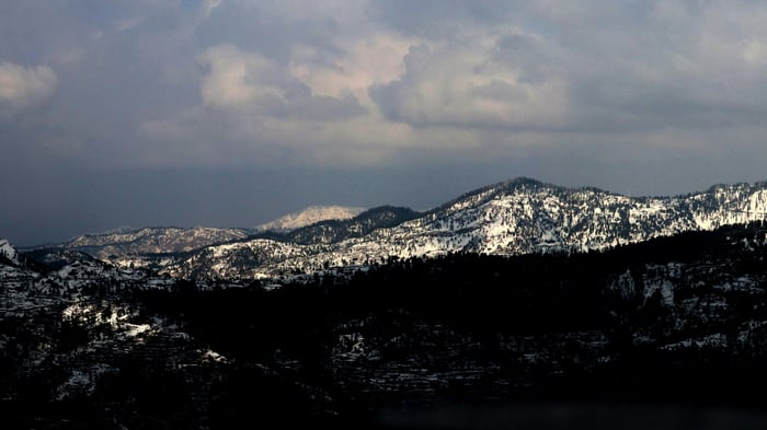 Snow-covered mountain range under cloudy sky