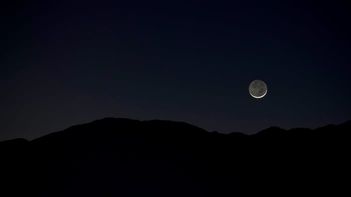 Crescent Moon Over Silhouetted Mountains