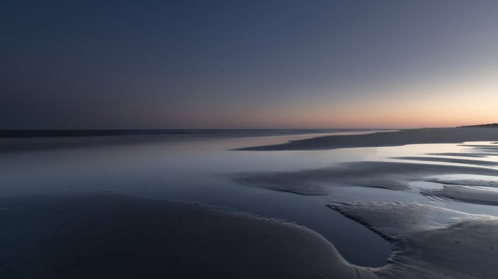 Minimalist seascape with calm ocean and wet sand