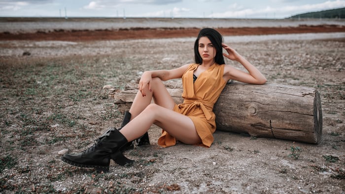 Woman in yellow dress sitting on a log outdoors