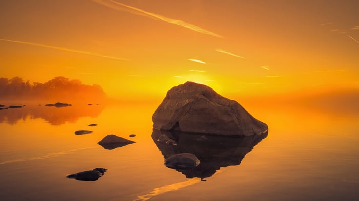 Sunset over water with rock formation and reflection
