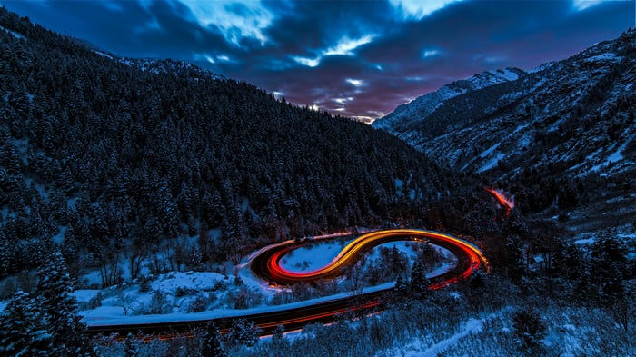 Snowy mountain road with light trails at dusk