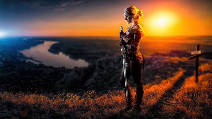 Ciri from The Witcher holding a sword at sunset
