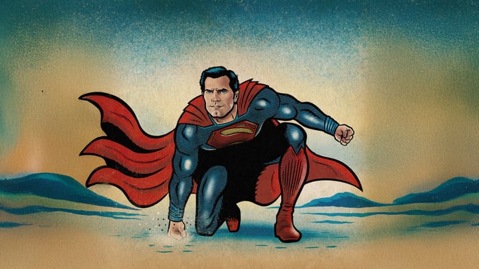 Superman kneeling on a sandy landscape