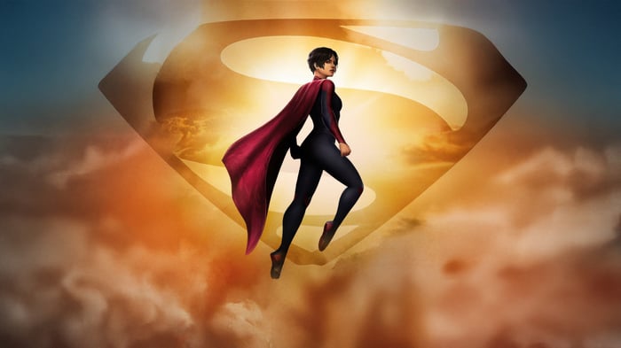 Supergirl in front of the Superman logo