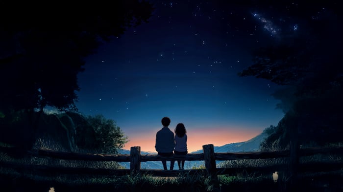 Couple sitting on a fence looking at the stars