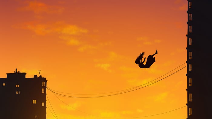 Silhouette of a girl falling between buildings at sunset