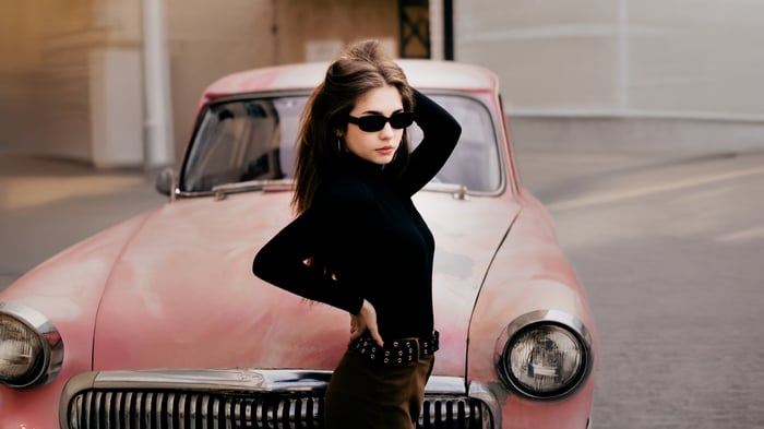 Model in Black Turtleneck Poses with Vintage Pink Car