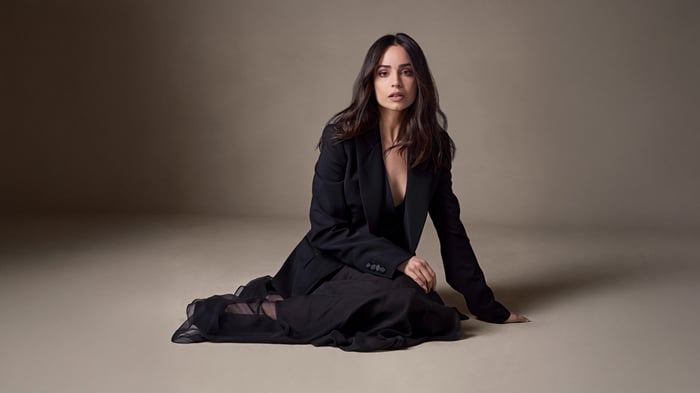 Model in black blazer and dress sitting on floor