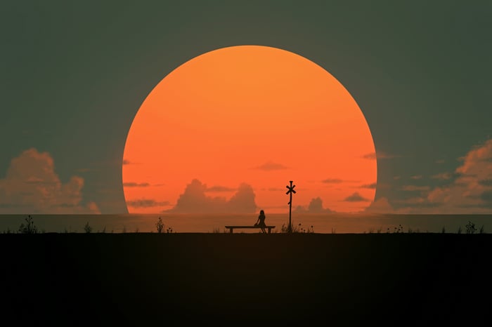 Person Sitting Alone At Sunset With Large Sun