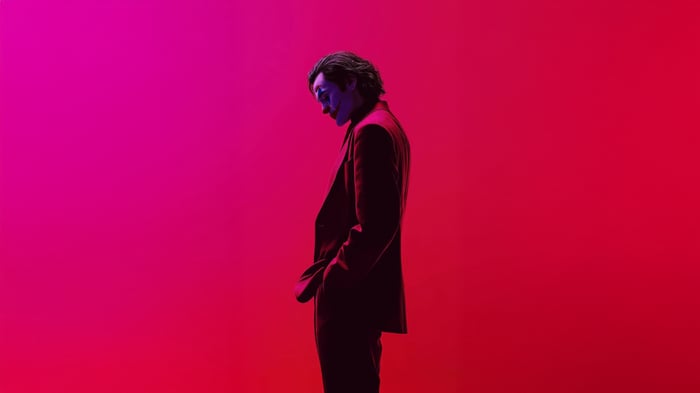 Joker in a purple suit against a pink and red background