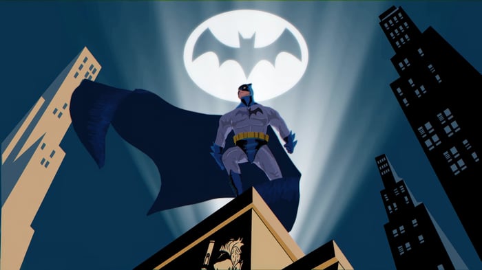 Batman standing on a rooftop with the Bat-Signal