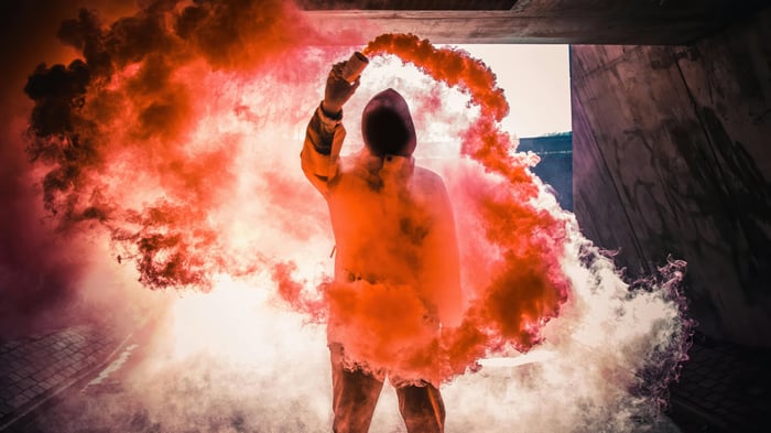 Person holding a smoke bomb in a concrete tunnel