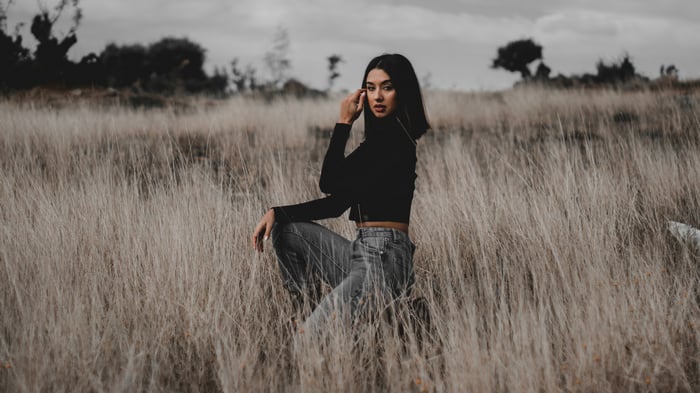 Model in black crop top and jeans in field
