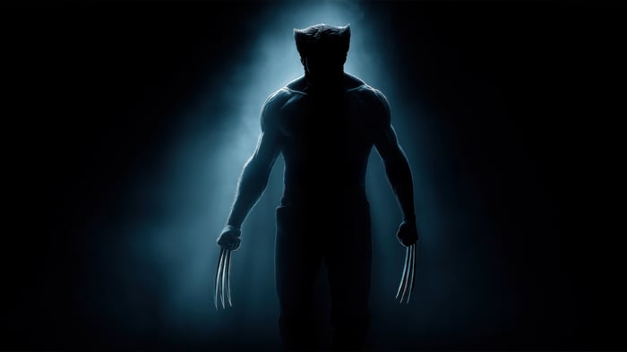 Wolverine stands in a dark, smoky environment with claws extended.