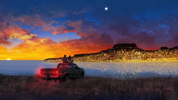 Couple on pickup truck overlooking city at sunset