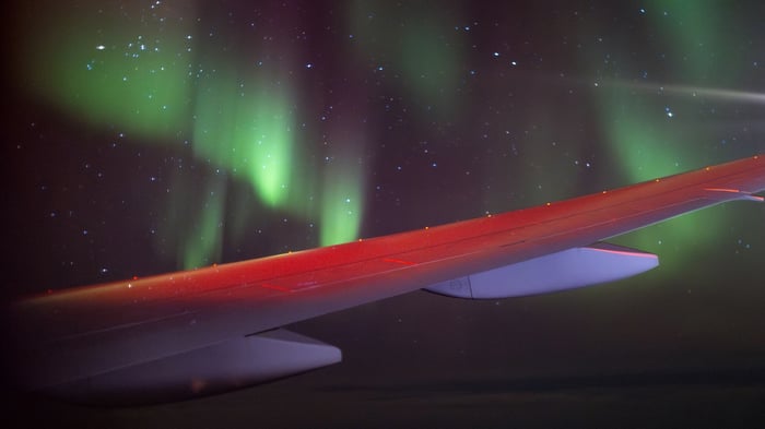 Airplane wing with aurora borealis and stars