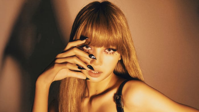 Lisa from BLACKPINK with long blonde hair and black nails