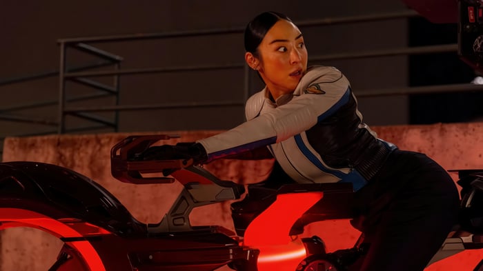 Greta Lee on a futuristic motorcycle